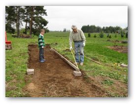 My husband and grandson measuring and preparing to build a raised bed vegetable garden