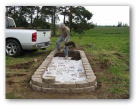 Paver raised bed lined with newspaper and being filled with raised bed soil