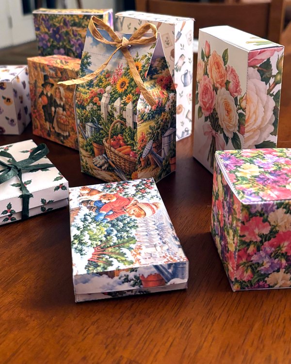 Free printable gable gift box with a garden harvest picture, tied with a raffia bow, in front of other printable gift boxes