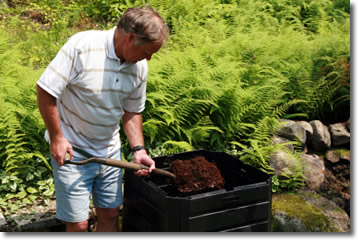 gardener shoveling compost out of a compost bin